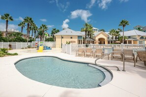 A swimming pool with a white deck, surrounded by palm trees and a white fence. - Oceanfront beauty in Cinnamon Beach - 824! (Palm Coast)