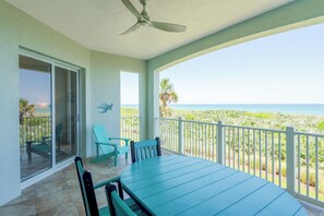 A balcony with a table and chairs, a ceiling fan, and a view of the ocean. - Oceanfront beauty in Cinnamon Beach - 824! (Palm Coast)