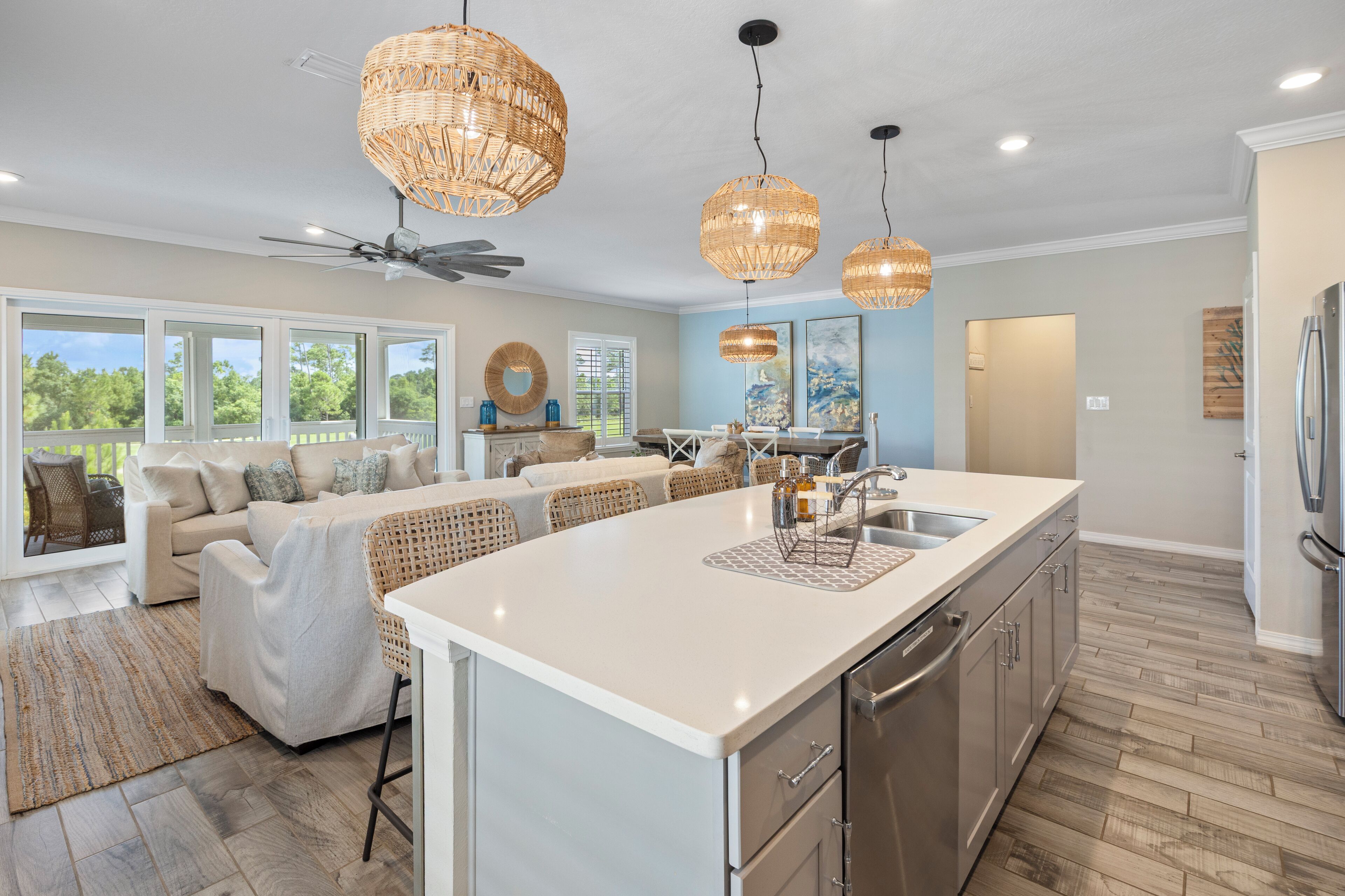 A spacious kitchen with a large island, modern appliances, and a dining area with wicker furniture.
