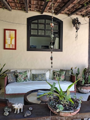 A cozy room with a bed, a hanging decoration, a wall-mounted lamp, and a framed artwork. - Pousada bela casa geriba (Buzios)