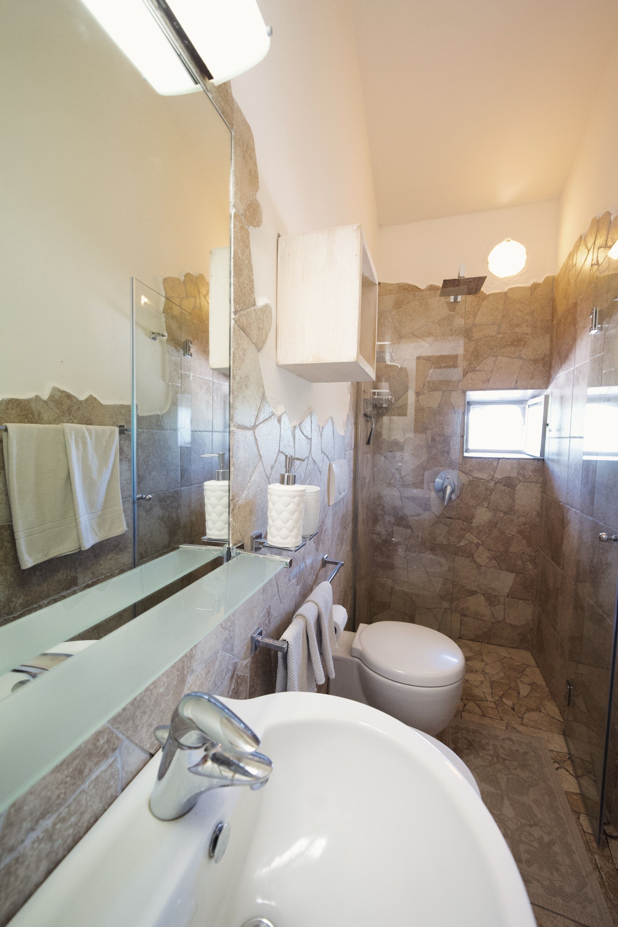 A bathroom with a glass shower enclosure, a white sink, and a toilet.