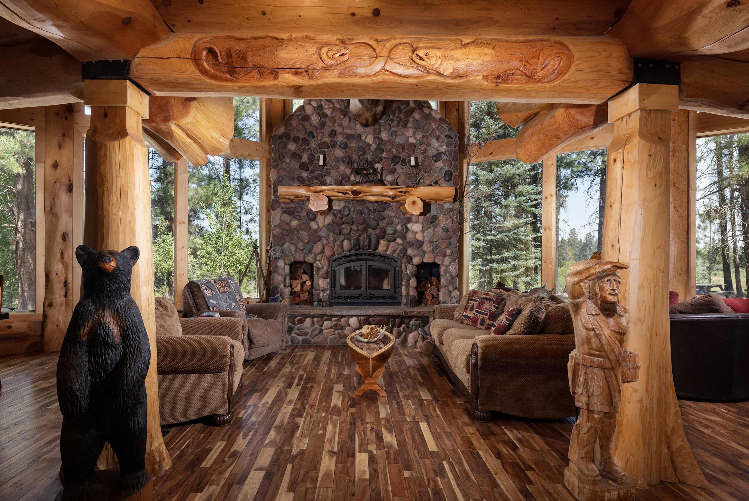 L’intérieur chaleureux d’un chalet avec une cheminée en pierre, des meubles en bois et une sculpture d’ours.