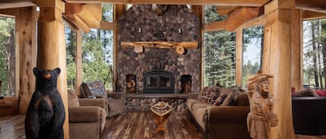 Interior acogedor de una cabaña con chimenea de piedra, mobiliario de madera y una escultura de oso.