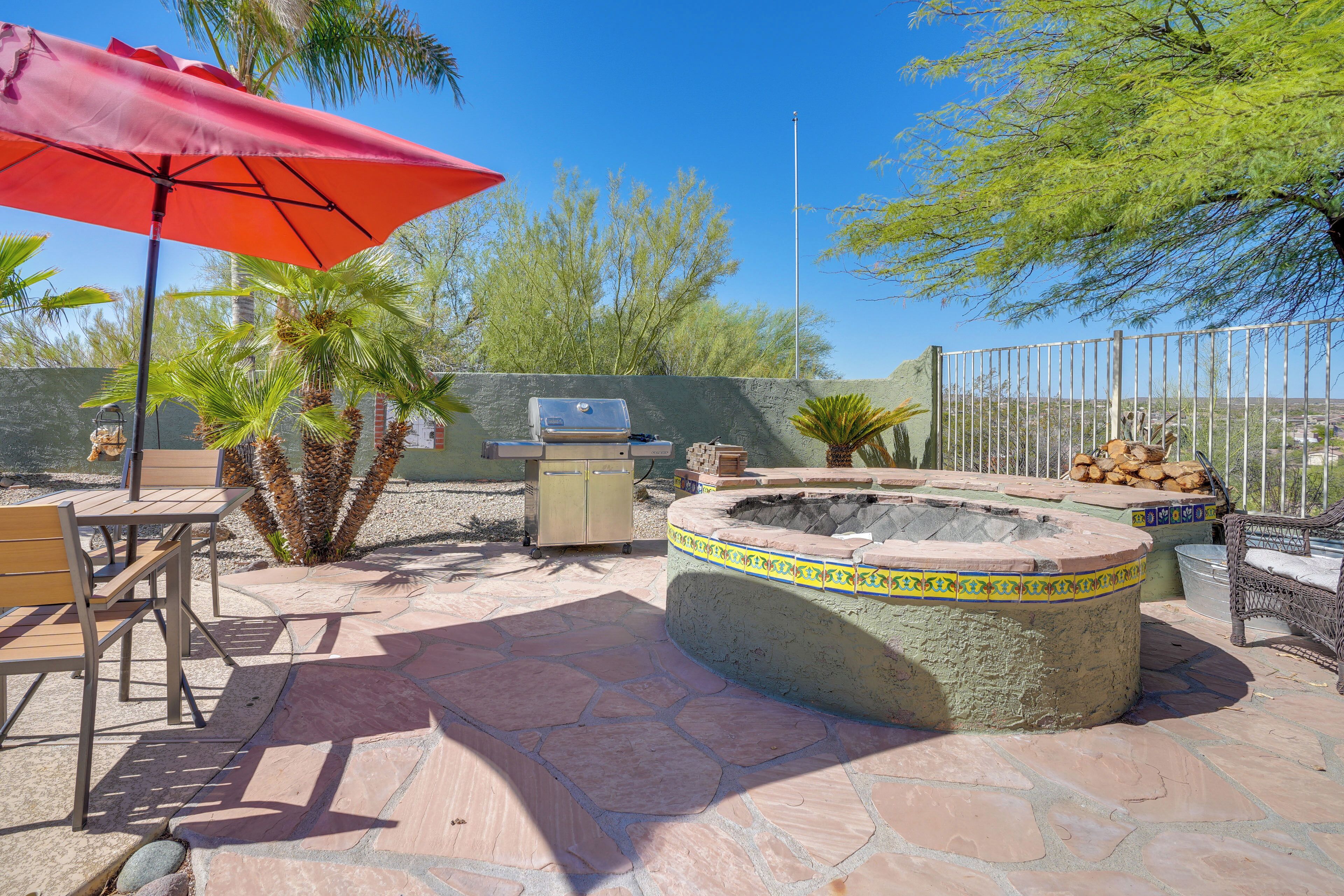 A patio area with a stone fire pit, outdoor furniture, and a grill.