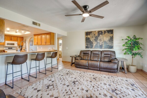 A modern kitchen with a bar area, a leather sofa, and a large rug.