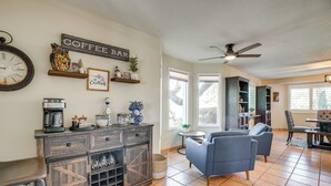 A cozy living room with a coffee bar, comfortable seating, and a large clock on the wall. - Backyard Oasis & Hot Tub: Mtn-view Wickenburg Home (Wickenburg)