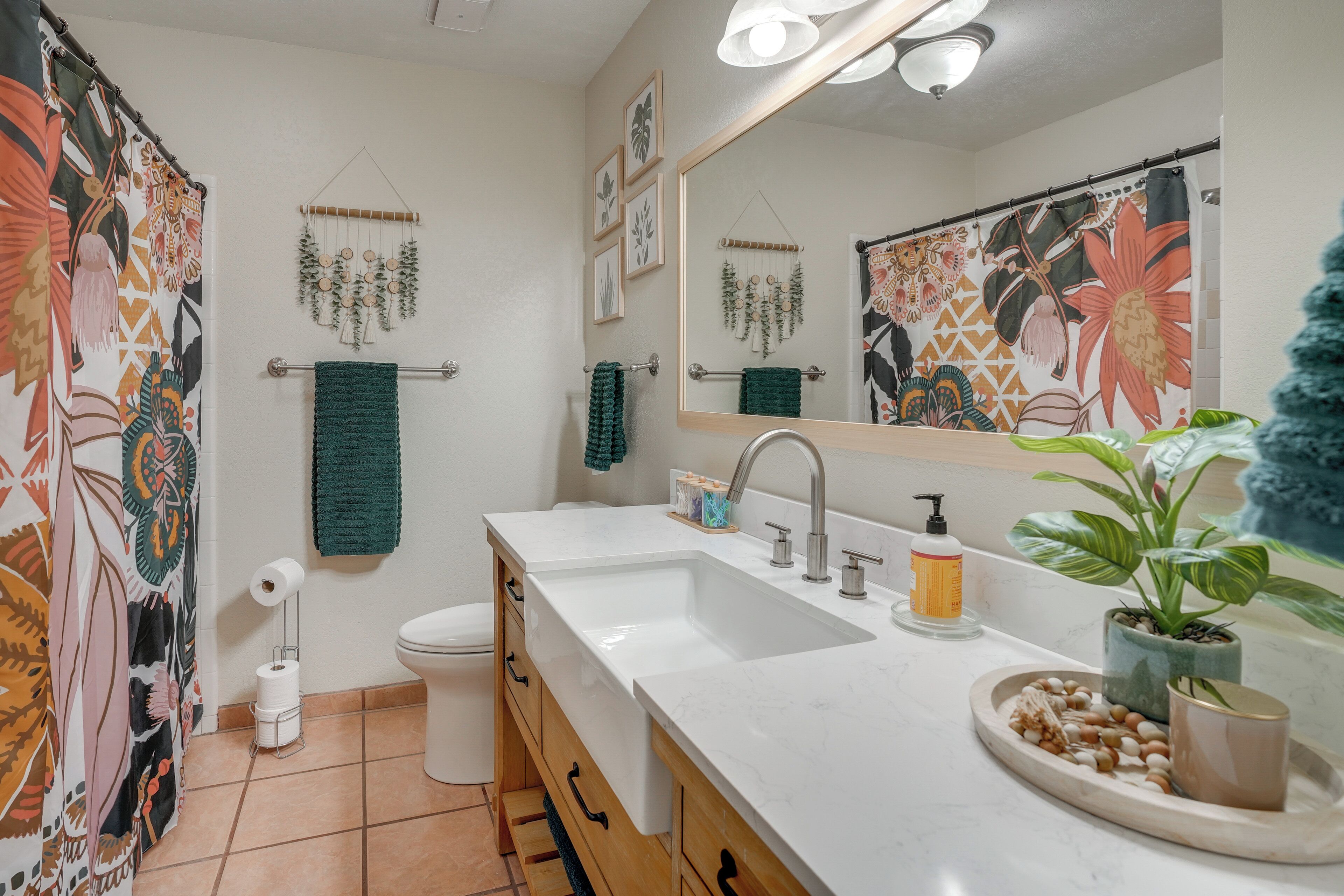 A bathroom with a white sink, a mirror, a toilet, and a shower curtain with a floral pattern.