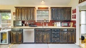 A kitchen with dark wooden cabinets, a granite countertop, a stainless steel sink, and a built-in microwave. - DFW Fun Awaits: Family Home in Crowley! (Crowley)