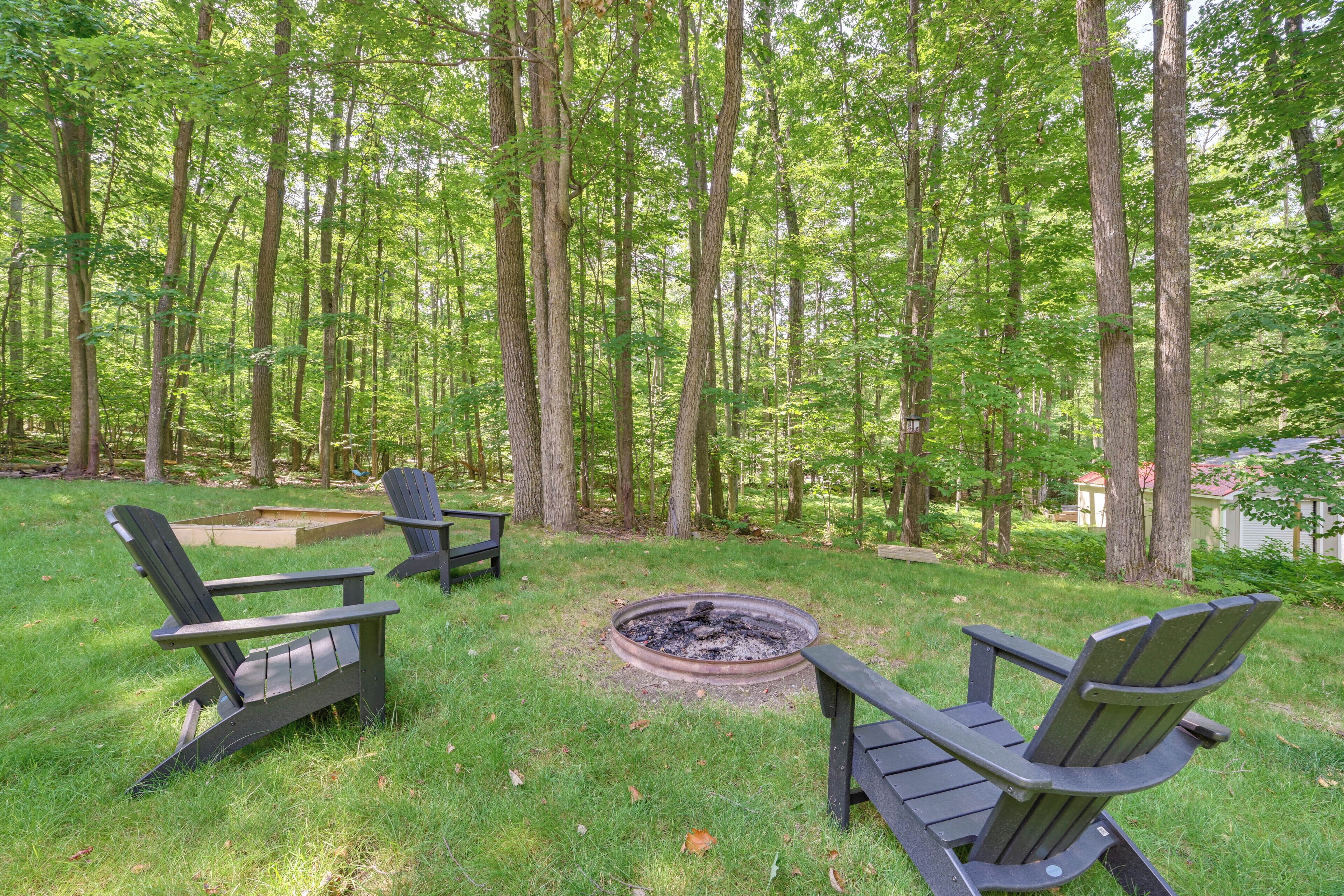A backyard with two Adirondack chairs, a fire pit, and a wooden deck.