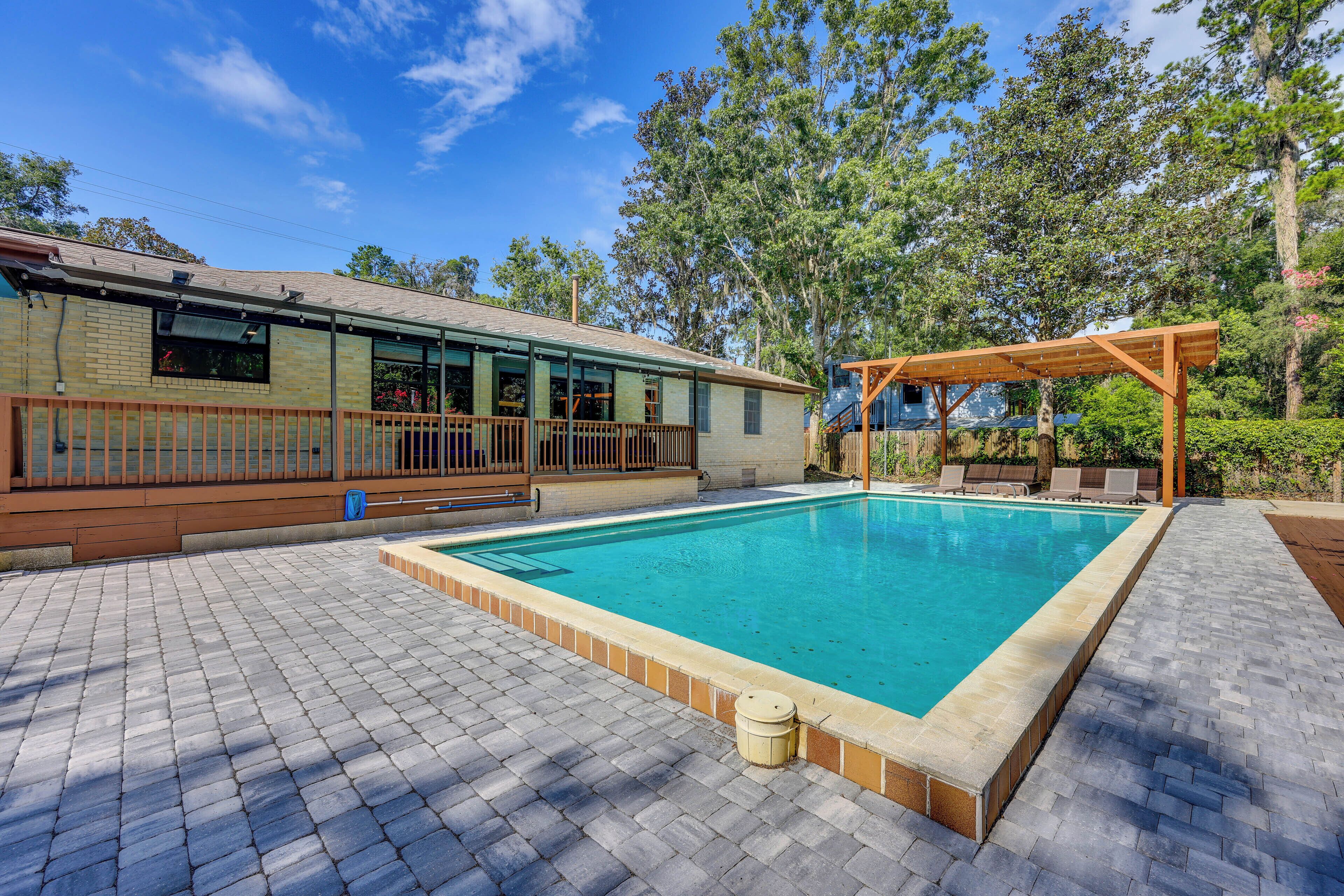 Ein Schwimmbecken mit Holzterrasse und überdachter Liegebereich.