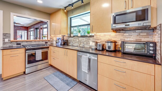 Une cuisine moderne avec des meubles en bois, des appareils électroménagers en acier inoxydable et une grande fenêtre.