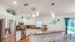 A modern kitchen with stainless steel appliances, white cabinetry, and a central island with bar seating.