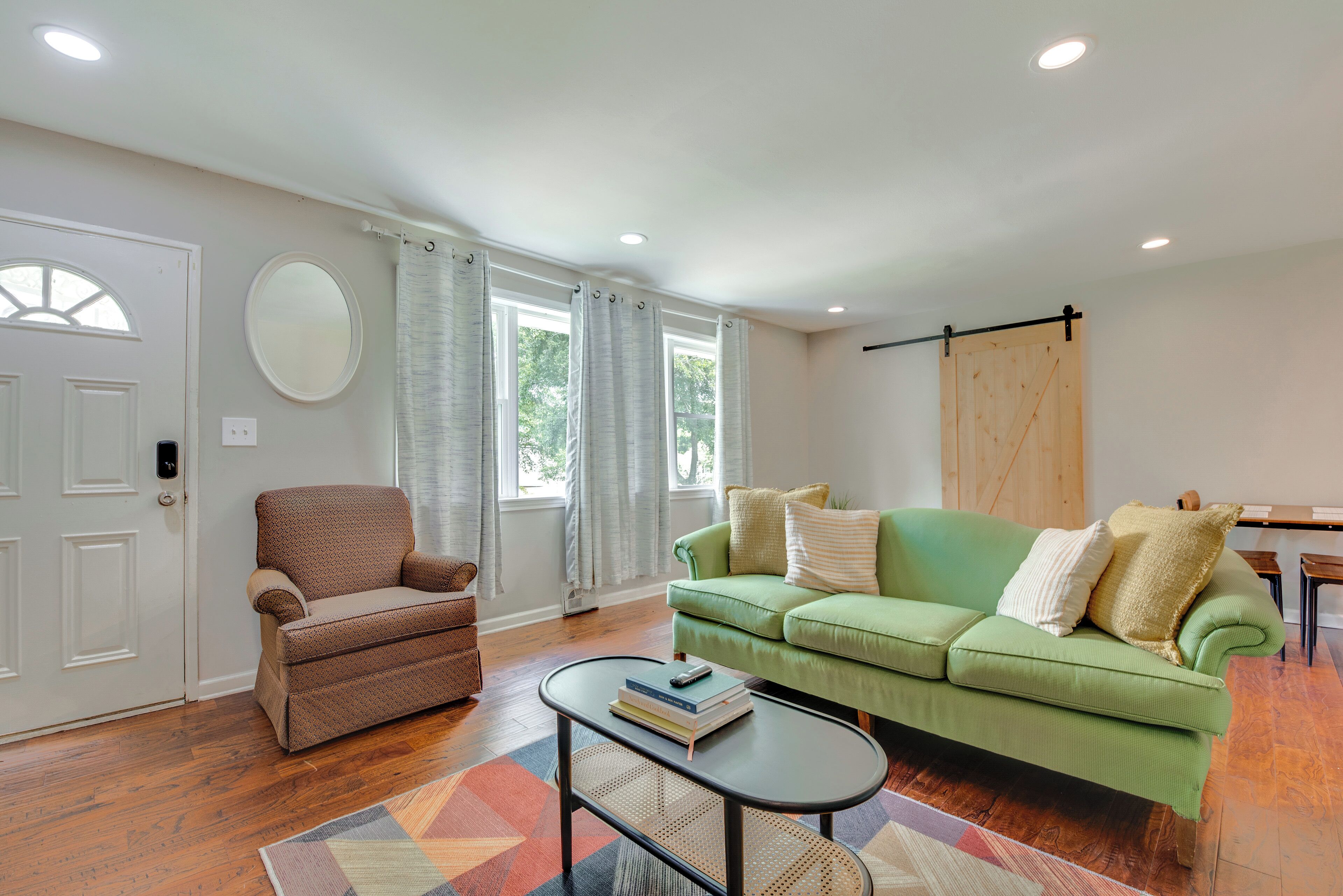 A living room with a brown armchair, green sofa, and a coffee table with books.