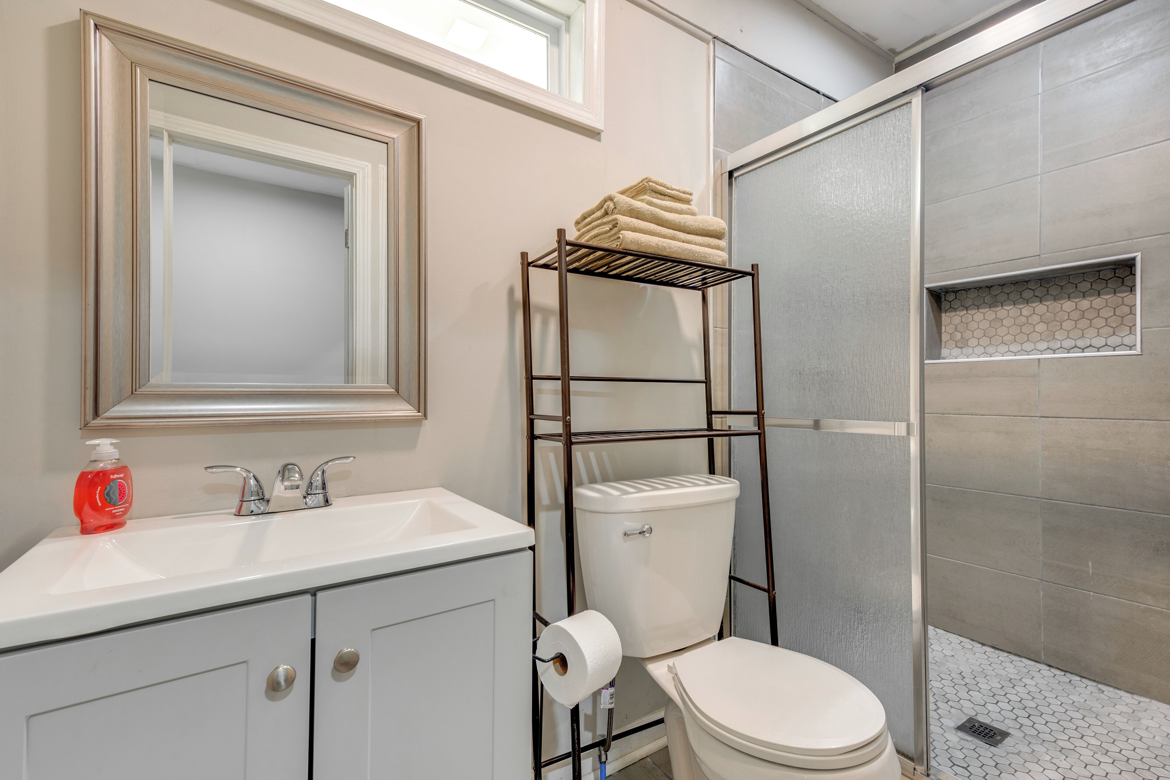 A bathroom with a white sink, a toilet, a towel rack, and a shower area.