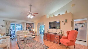 A spacious living room with a sofa, armchair, and coffee table, a kitchen with a refrigerator, and a ceiling fan. - Tampa Home w/ Private Backyard ~ 15 Mi to Downtown (Tampa)