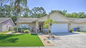 A single-story house with a garage, a well-maintained lawn, and a variety of plants. - Tampa Home w/ Private Backyard ~ 15 Mi to Downtown (Tampa)