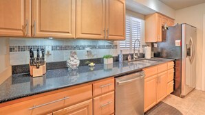 A kitchen with wooden cabinets, a stainless steel refrigerator, and a black granite countertop. - Tampa Home w/ Private Backyard ~ 15 Mi to Downtown (Tampa)