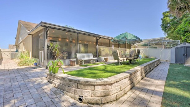 A modern house with a patio area featuring a stone planter, a bench, and outdoor furniture. - Tampa Home w/ Private Backyard ~ 15 Mi to Downtown (Tampa)