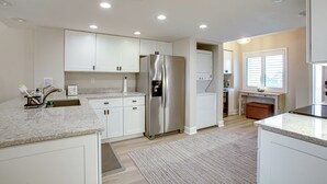 A modern kitchen with white cabinets, a stainless steel refrigerator, and a granite countertop.