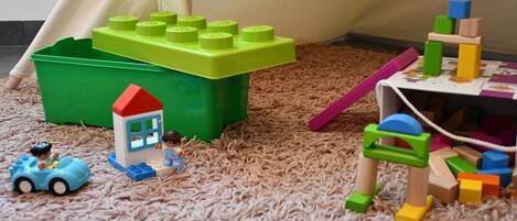 A play area with a green bin, a small blue car, and a tent.