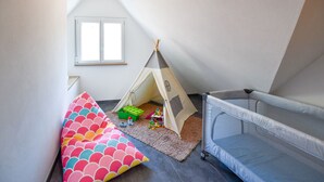Una stanza con un letto a soppalco, una tenda gioco e un pouf colorato.