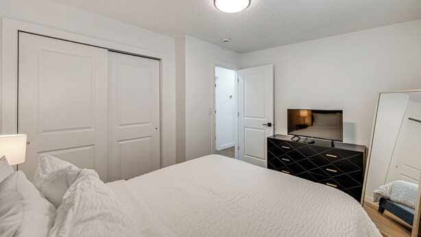 Ein Schlafzimmer mit Bett, Kommode, Fernseher und Tür.