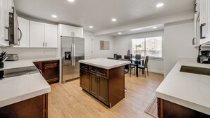 Una cucina moderna con mobili bianchi, un'isola centrale e un'area pranzo con tavolo e sedie.