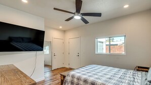 Ein Schlafzimmer mit einem Bett, einer hölzernen Bank, einem Deckenventilator und einem Fenster.