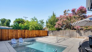 Ein Garten mit Pool, Grill und Holzzaun.