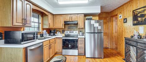 A kitchen with wooden cabinets, stainless steel appliances, and a herringbone-patterned rug.