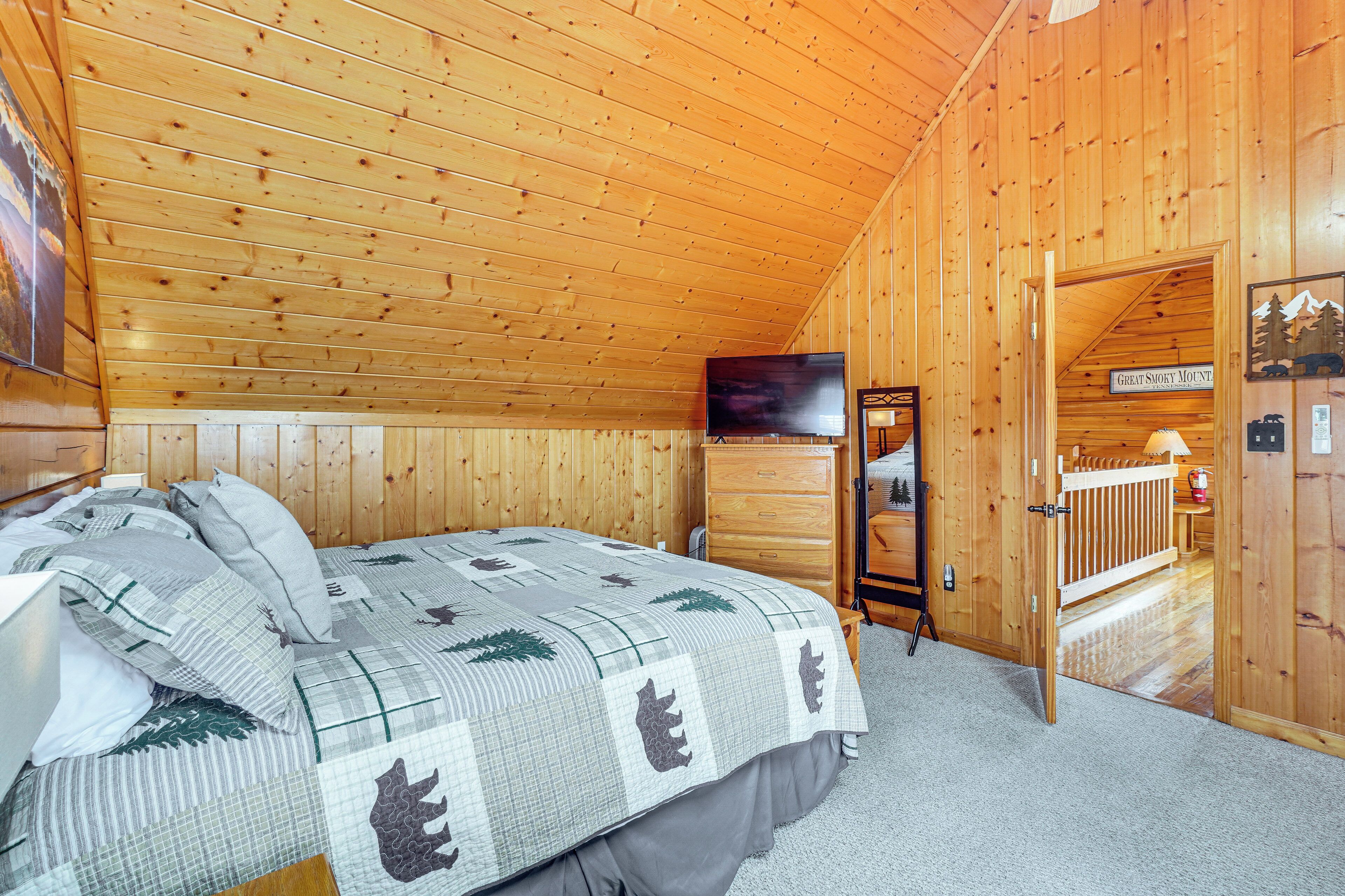 Quarto de cabana de madeira com cama, televisão e porta que dá para uma varanda.