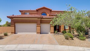 A two-story house with a red-tiled roof, a garage, and a landscaped front yard with small shrubs and a tree. - Las Vegas Escape w/ Private Outdoor Paradise (Las Vegas)