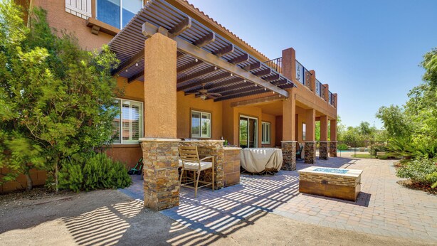 A covered patio area with outdoor seating, a stone bench, and a table with a tablecloth. - Las Vegas Escape w/ Private Outdoor Paradise (Las Vegas)