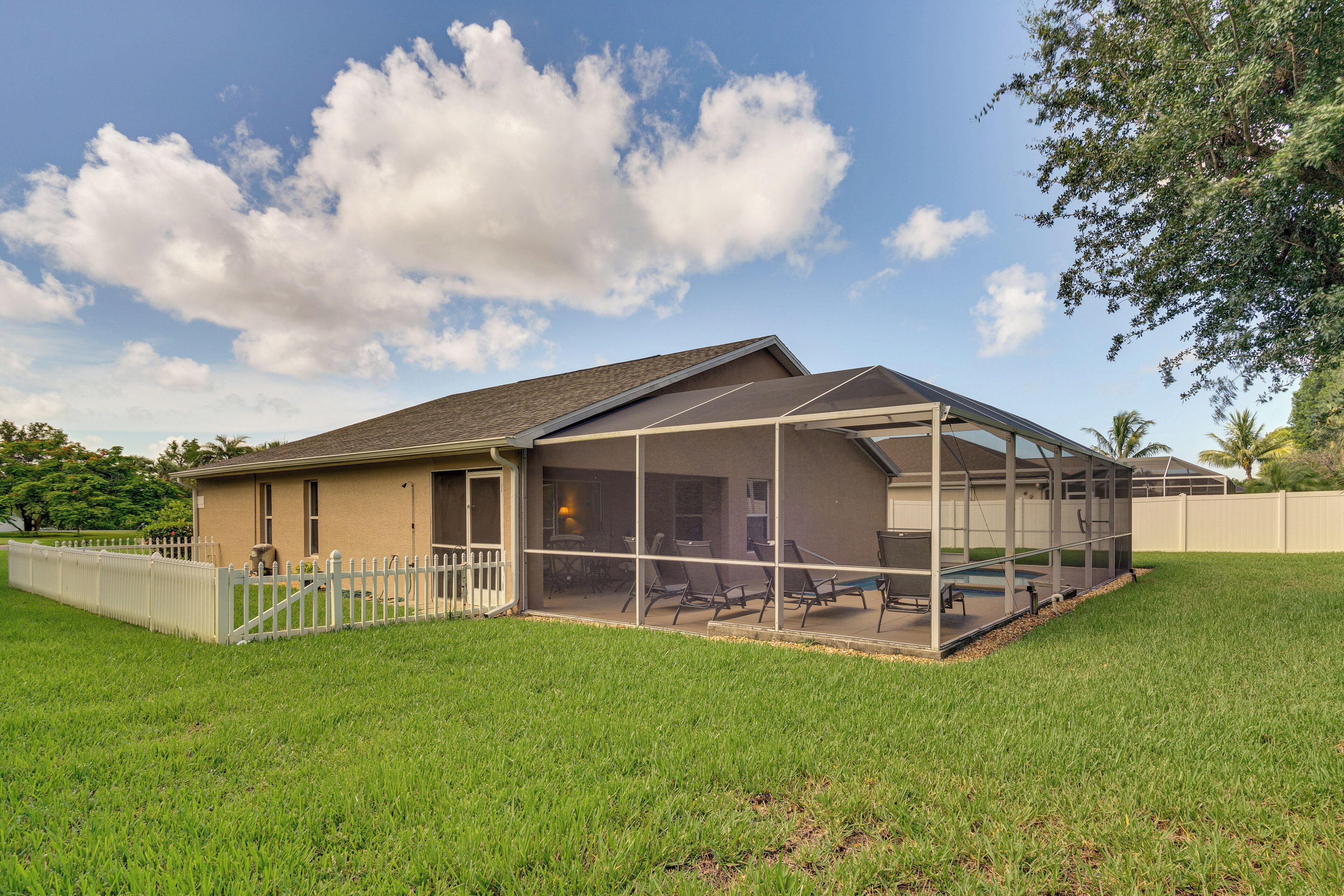 A house with a covered patio, a fenced yard, and a clear sky.