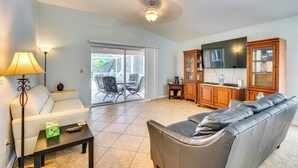 A living room with a sofa, a coffee table, a lamp, and a TV. - 4 Mi to Beaches: Fort Myers Escape w/ Patio (Fort Myers)