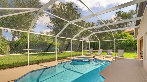 A covered outdoor swimming pool with a clear view of the surrounding greenery and a house in the background. - 4 Mi to Beaches: Fort Myers Escape w/ Patio (Fort Myers)