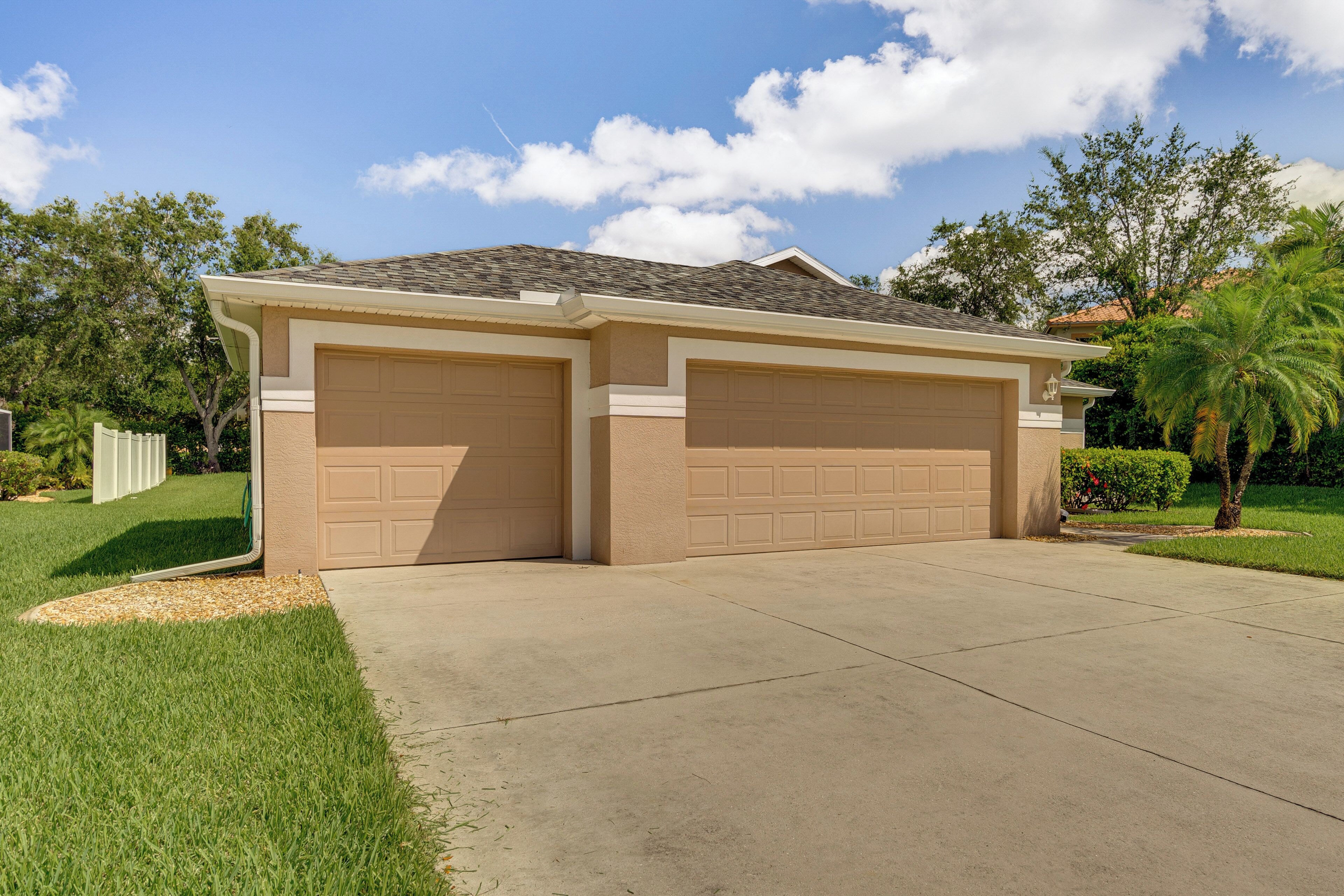A two-car garage attached to a house with a sloped roof and beige siding.
