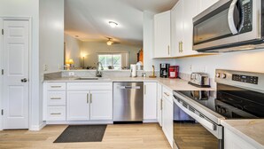 A modern kitchen with white cabinets, stainless steel appliances, and a black countertop. - 4 Mi to Beaches: Fort Myers Escape w/ Patio (Fort Myers)