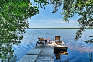 A wooden dock extending into a calm lake, with two chairs and a small table. - Cozy Lakefront Madison Cabin w/ Dock & Kayaks (Madison)