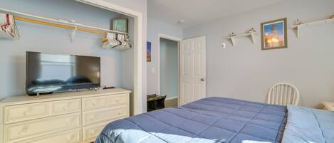 A bedroom with a bed, a dresser, a television, a ceiling fan, and a door.