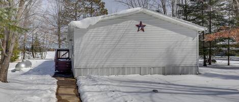 Un edificio blanco con una estrella roja en el techo, rodeado de nieve y árboles.