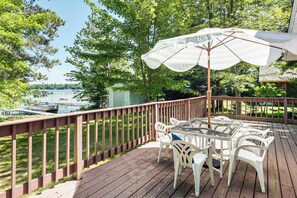A wooden deck with a glass table and chairs, overlooking a lake. - Solberg Lake House: Dock, Deck + Stunning Views! (Phillips)