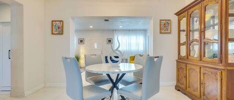 A dining area with a round table, four chairs, and a wooden cabinet.