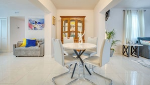 A modern living room with a dining area, featuring a round table and chairs, a sofa, and a potted plant. - 2 Mi to Hard Rock Stadium: Home w/ Spacious Yard (Miami Gardens)