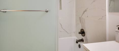 Een moderne badkamer met een douche, een bad en een wastafel.