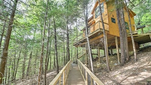 A wooden treehouse with a wooden deck leading up to it, surrounded by a forest. - Tree House w/ Hot Tub: Near Sunday River Resort! (Rumford)