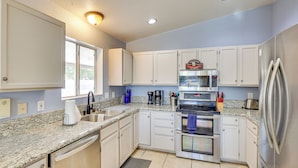 A modern kitchen with white cabinets, granite countertops, stainless steel appliances, and a window providing natural light. - 5 Mi to CO River: Home w/ Pool in Fort Mohave! (Fort Mohave)