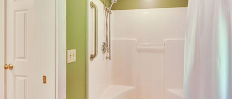 A bathroom with a shower, a door, and a light switch.