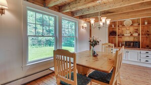 A wooden dining table with chairs, a chandelier, and a view of the outdoors through large windows. - Rural Retreat 3 Mi to Morrisville & Rail Trail! (Hyde Park)