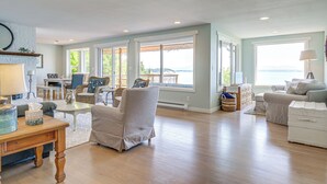 Een ruime woonkamer met een groot raam, een open haard en uitzicht op de oceaan.